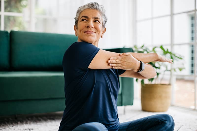 Happy and healthy senior woman doing a cross arm stretch