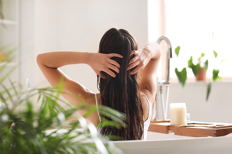 Young woman applying coconut oil onto her hair